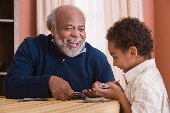 grandparent laughing while playing cards with grandchild