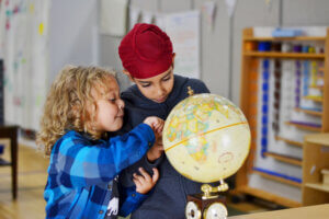 Battle Creek Montessori Academy students look over a globe together in the classroom. 